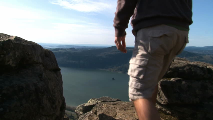Person hiking and and sitting on rocks atop cliff in Oregon up the Gorge.