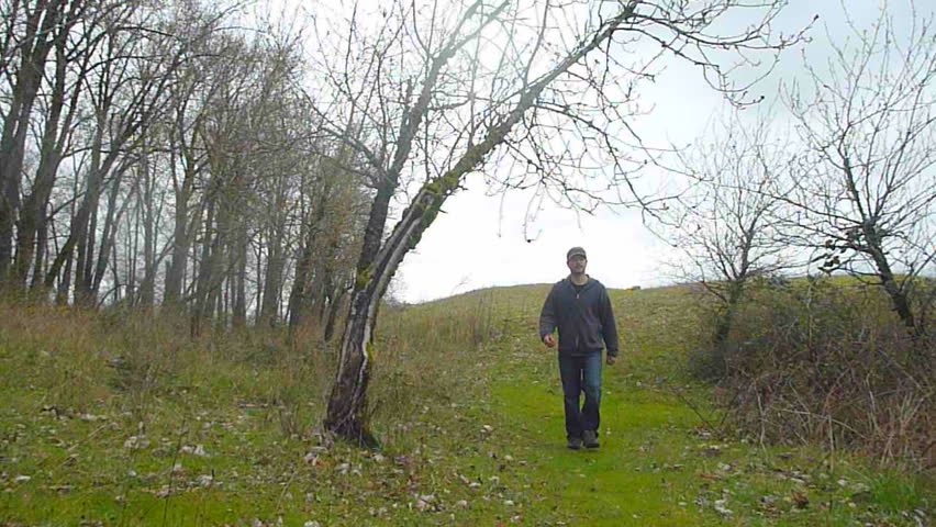 Man hiking towards camera down grassy hill on a solo adventure.