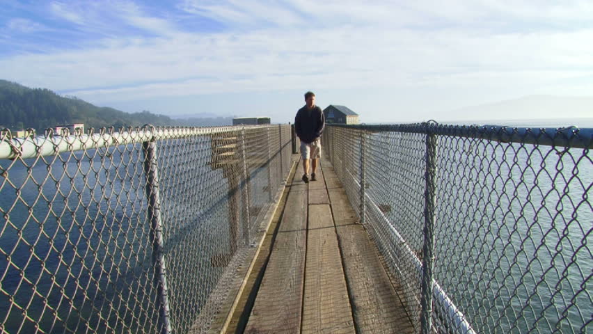 Man walking towards camera in Oregon on ocean pier.