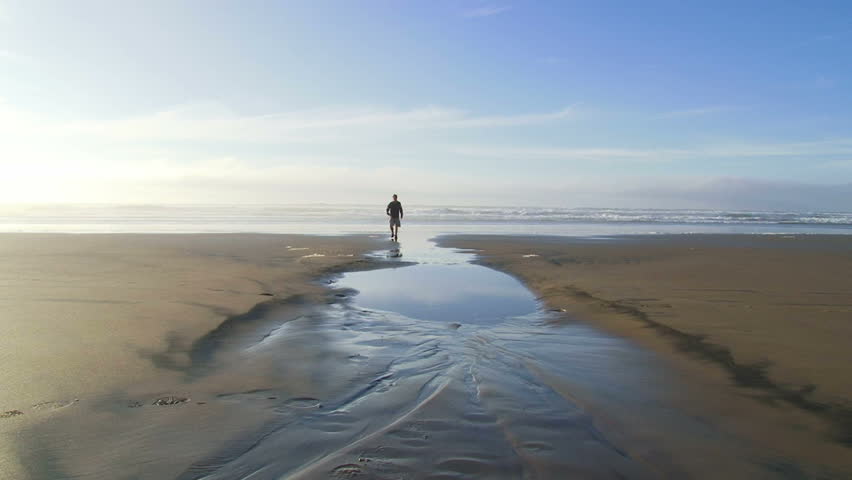 Man enjoying sandy beaches of the Pacific Ocean in Oregon with his black lab