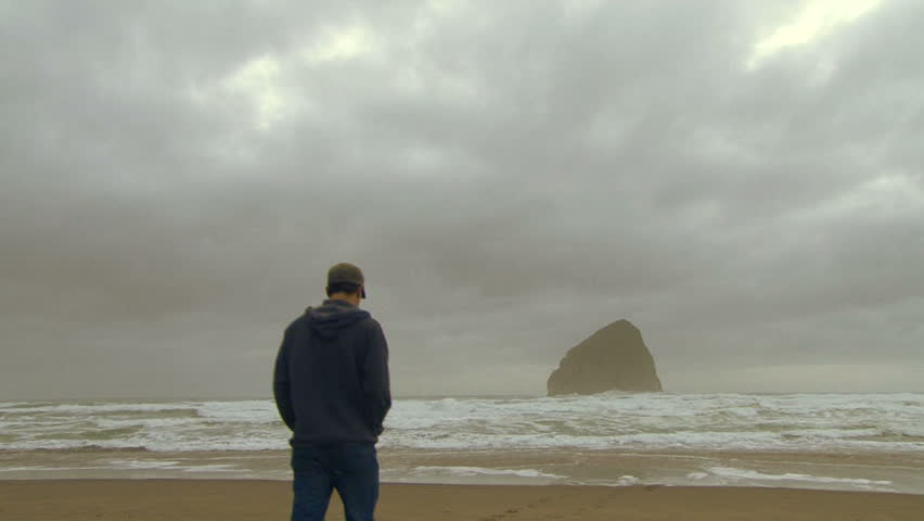 Man walks towards coast at Pacific Ocean.