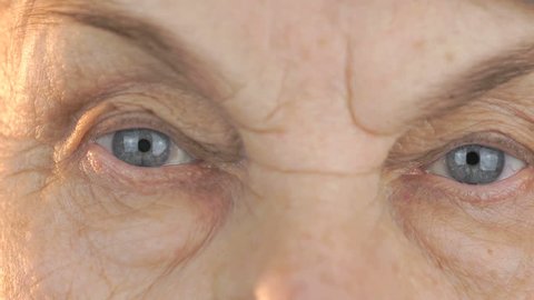 Old woman looks through the eyes in different directions. Close up