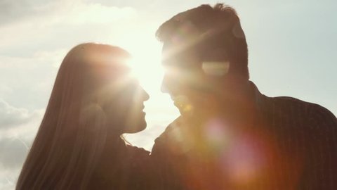 Few shots of young couple darken silhouette kissing and smiling on a bright sunlight. Love story. Being happy together. Happy moments. Outside shooting, sun lens.