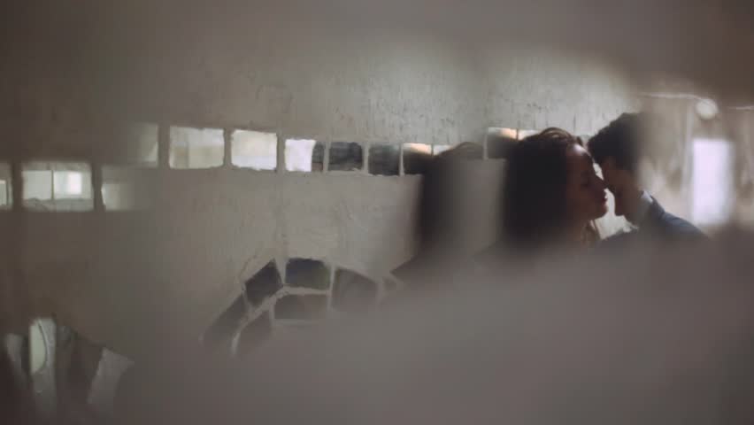 Passionate couple kiss. Amazing brunette attractive girl and elegant young guy, kissing on the corner of the street by the wall, no people around. Love story. Forever together, being in love.