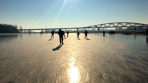 Ice skating people on a frozen lake near the river IJssel in The Netherlands during a beautiful winter day