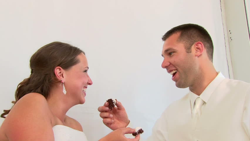 Model released bride and groom cut the cake and feed each other and laugh on