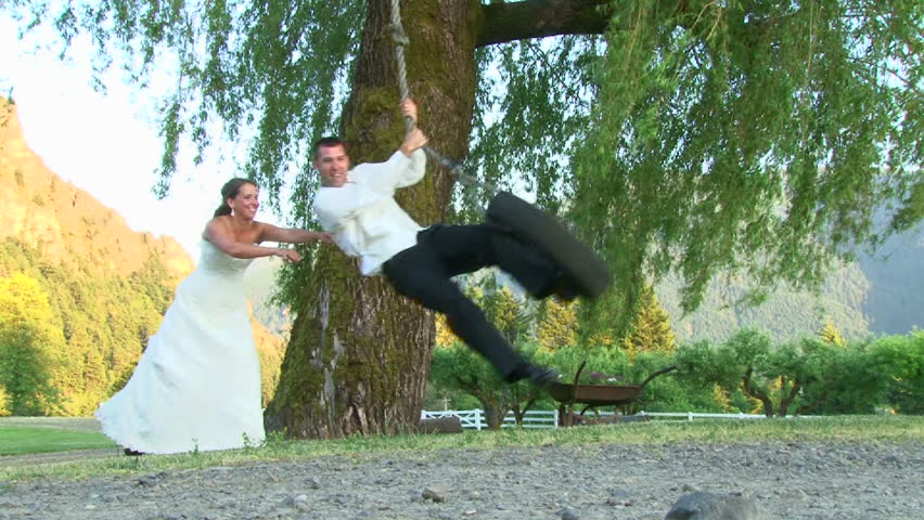 Bride gives her Groom a push on the tire swing on their wedding day.