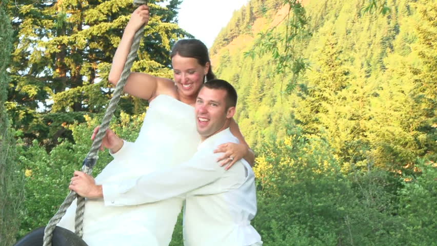 Bride gives her Groom a quick kiss on their wedding day from tire swing.
