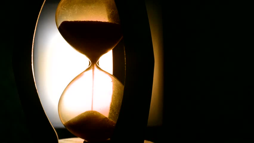 Time concept. Silhouette of Hourglass clock and old vintage wood clock with arrow and smoke on dark background with hot yellow orange  blue cold back lighting, or symbols of time under smoke, the end | Shutterstock HD Video #23394127
