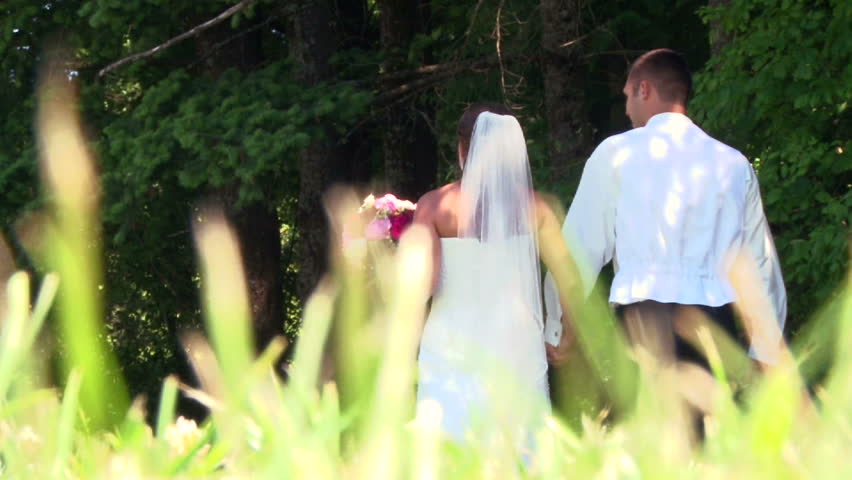 Bride and groom walking together in forest on their wedding day.