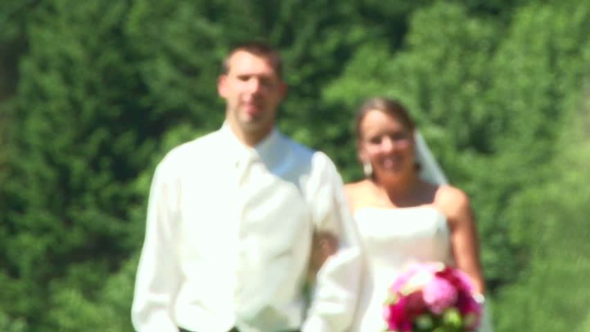 Model released bride and groom walk toward camera, low angle camera, in green