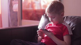 Young boy playing game on smartphone in home
