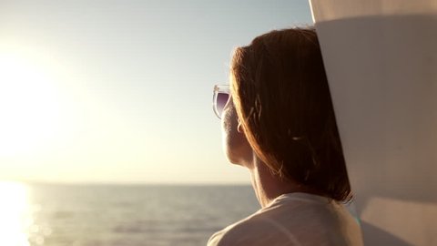 CLose up footage of Caucasian female looking at sea through sunglasses while sun shining in slowmotion