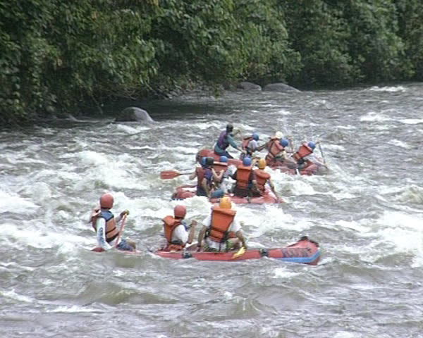 People in rubber boats sail down wildwater river. Extreme risky recreation.