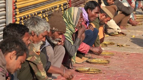 VARANASI, INDIA - JANUARY 25, 2017 : Unidentified poor indian people eating free food at the street near river ganges in Varanasi, India