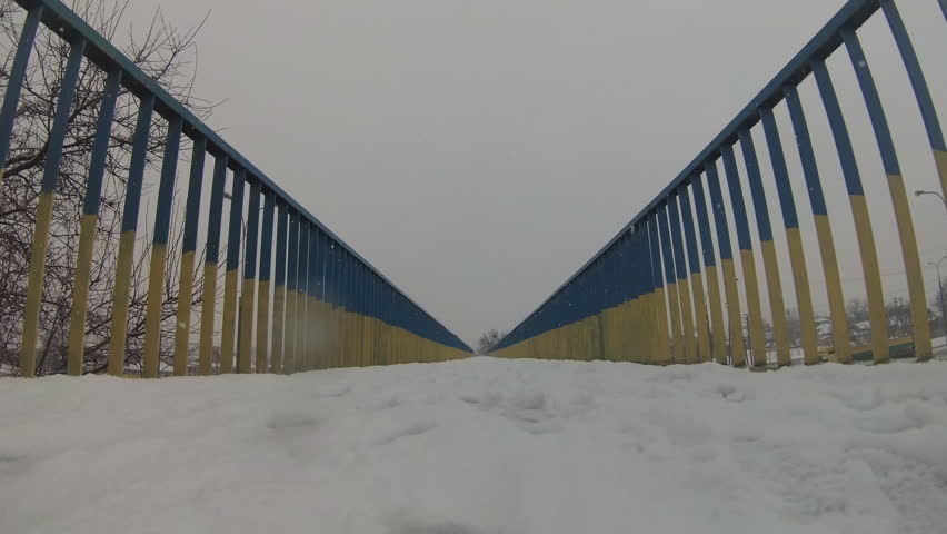 Perspective metal pedestrian bridge painted in the traditional colors  Ukrainian flag in winter day. Ukraine.