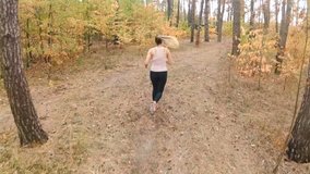 Slow motion video of young woman running on path at forest