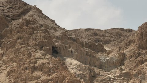 zoom in on a cave in the hills at qumran where the dead sea scrolls were discovered in israel