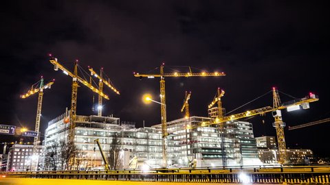 Construction site at night Time Lapse. Working tower cranes, buildings and traffic