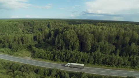 Semi Truck drives in forest road asphult aerial view top