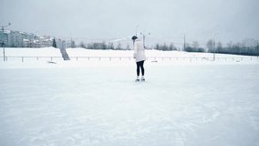 Young blonde woman skating on ice rink in a park