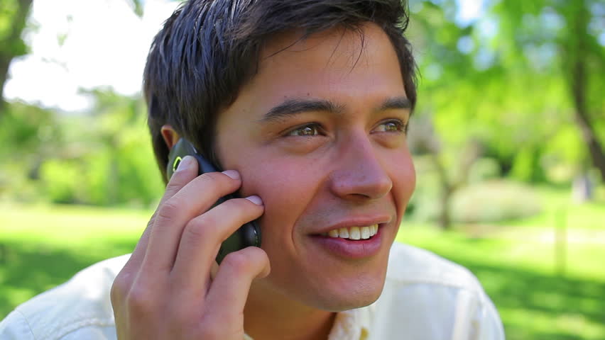 Happy man using his mobile phone in a parkland
