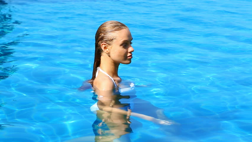 Sexy woman resting in blue water of swimming pool

