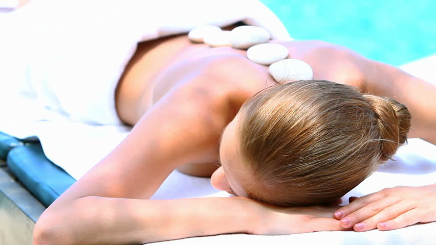 Woman taking hot stones massage in tropical outdoor
