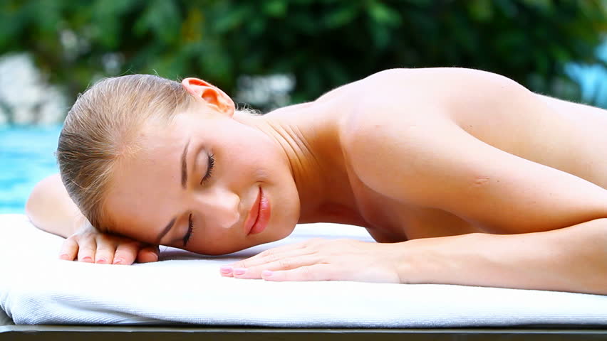 Adorable woman lying on spa bed in tropical outdoors

