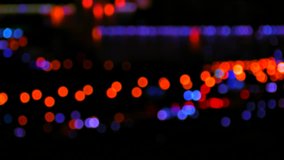 Moving bokeh circles of night traffic against black blurred city background. 