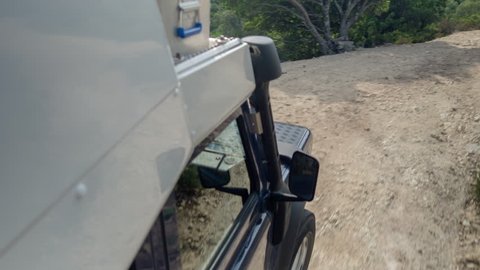 a shot from a camera attached to the side of an off road campervan driving on rough tracks in sardinia, italy