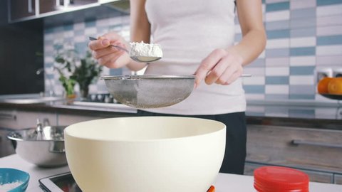 Young woman  sieve flour before kneading, slow motion, close up