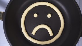 Hurt Emoticon made from butter. Accelerated Video, butter melts in a skillet.