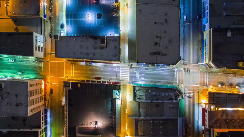 Top down aerial timelapse view of traffic on illuminated street intersections and city blocks in Downtown, Los Angeles. Camera is flying up and rotating. Kaleidoscopic effect 