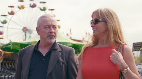Mature middle-aged lady and gentleman out on a date at a carnival