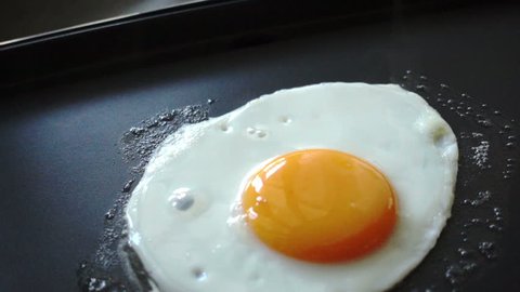 Fried egg cooking on a hot pan, slow motion