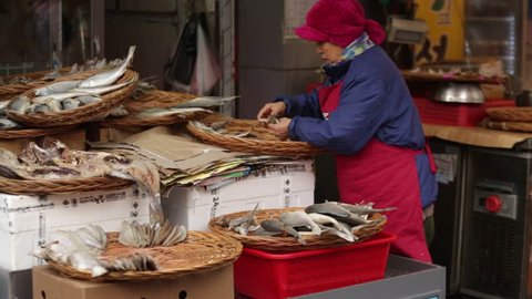 The seller puts the fish at the counter. Traditional seafood market in Asia.