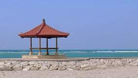 Small pagoda. with its traditional. tiled roof. stands on a jetty over the calm waters of a Balinese. tropical beach paradise.