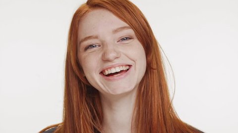 Close footage of young Caucasian red haired teenage girl smiling laughing on white background in slowmotion