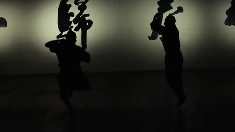 Two Shaolin monks demonstrate in silhouette their ancient form of kung fu. Shot in slow motion. 