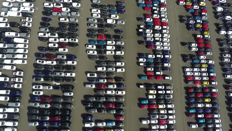 Aerial top down bird view new car storage parking lot showing imported new vehicles or ready to export new automobiles storage facility car industry for American and European market for car sales 4k