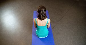 Woman doing yoga exercise in studio 4k back top view video. Fit athletic girl sitting on mat and stretching on asana posture. Fitness sport training