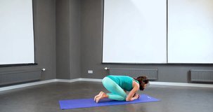 Woman doing yoga exercise in studio 4k video. Fit athletic girl balancing on head and arms. Headstand asana posture and pilates position
