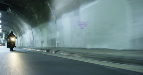 Tracking shot of a motorcycle speeding through a tunnel at night