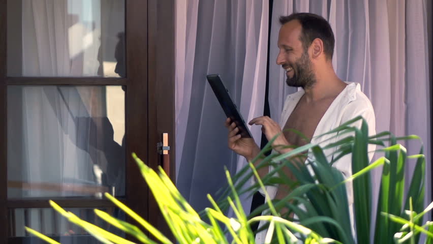 Young, happy man using tablet computer on terrace, super slow motion 240fps
