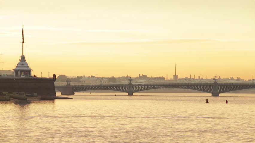 Russia, Saint-Petersburg, 29 June 2016: Panorama of prospect of Troitsky Bridge at sunrise, Peter and Paul Fortress, orange sky, dramatic clouds, Neva river, water area, spire, people playing sports