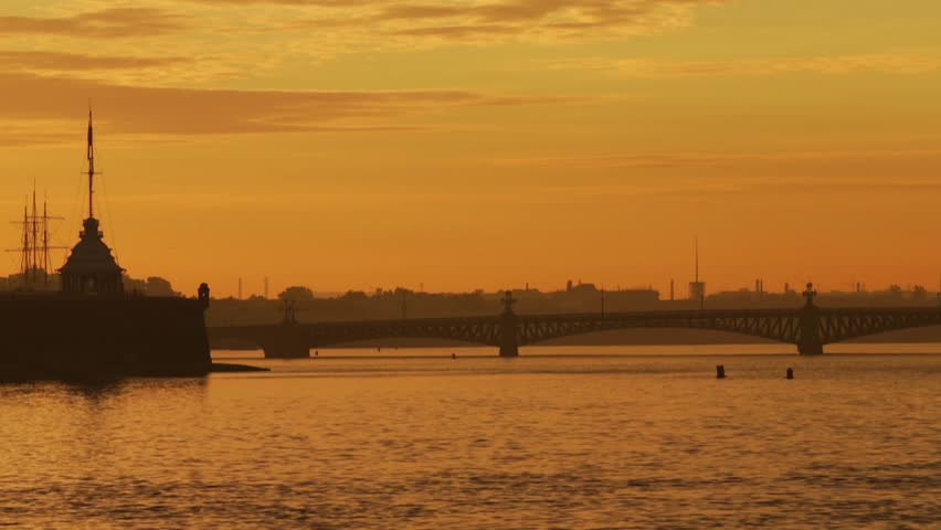 Russia, Saint-Petersburg, 29 June 2016: Panorama of prospect of Troitsky Bridge and Peter and Paul Fortress at sunrise, orange sky, dramatic clouds, Neva river, water area, spire