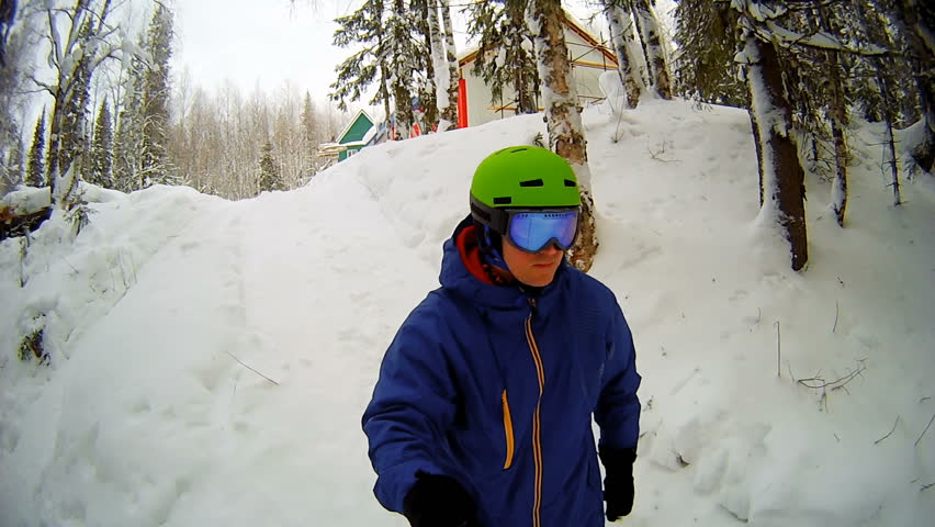 Man riding on snowboard with selfie stick in his hand