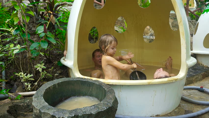 Father, mother and three or four year old child swimming in the mud bath.