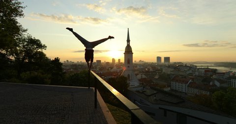 Young Man Doing Handstand on the Rail During Sunrise